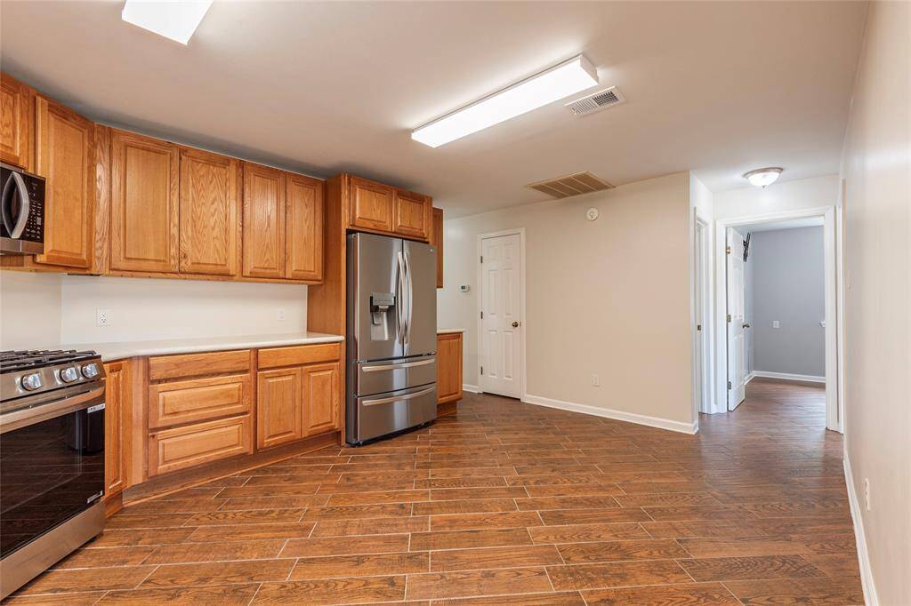 Very spacious kitchen area with vinyl plank flooring, stainless steel appliances, wood cabinets and more.