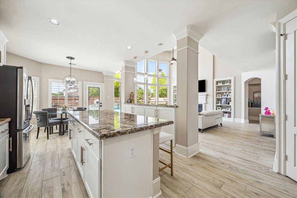 This stunning two-story living room offers a dramatic view with soaring ceilings and an expansive wall of windows that flood the space with natural light and showcase the beautiful backyard and pool.