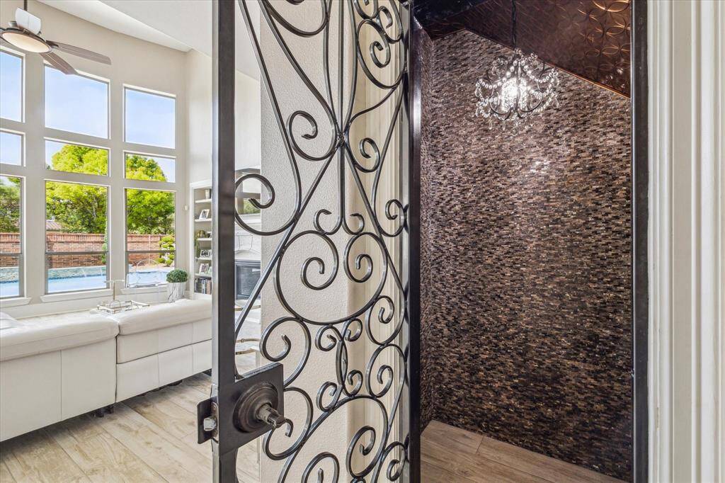 The breakfast nook features large windows with plantation shutters, filling the space with natural light. A decorative iron door leads outside, offering a charming view of the pool area.