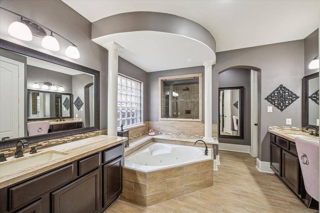 The primary bath is accented with architectural columns that frame a large jetted tub, a large walk-in shower, and a private toilet closet--all designed to create a relaxing retreat.