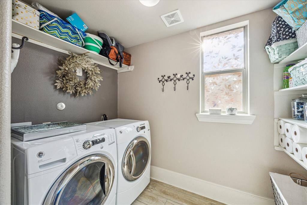 This bright and functional laundry room features built-in shelving, a hanging rack, and a large window with frosted privacy film that lets in natural light while maintaining privacy. Thoughtful design and ample storage make it a stylish and efficient space for everyday chores.