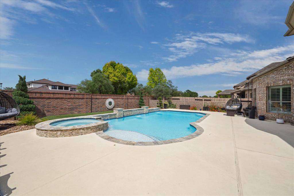 This view showcases the full saltwater pool framed by a spacious deck and a beautiful brick privacy wall. With no back neighbors, the setting offers enhanced seclusion—perfect for peaceful lounging and outdoor entertaining.