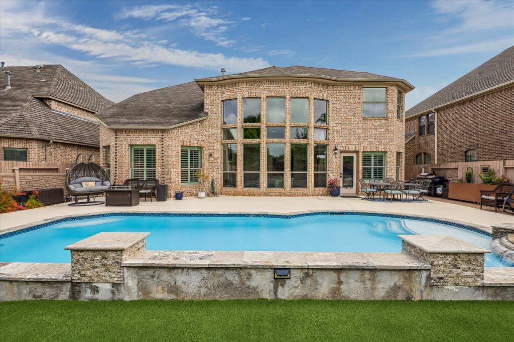 Relax by the backyard pool with soothing waterfall features and plenty of cool deck seating. With artificial turf and no grass to mow, it's a low-maintenance space perfect for unwinding or entertaining.