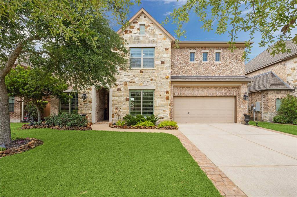 This elegant entryway showcases a grand staircase with wrought iron railings, soaring ceilings, and abundant natural light. The open layout flows into a cozy living area, highlighted by wood-looking, porcelain tile flooring throughout downstairs.