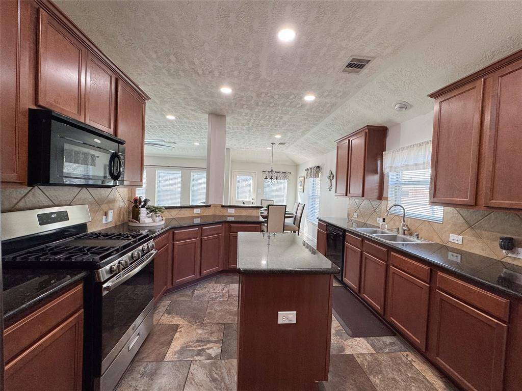 Kitchen equipped with gas range, large island, ample storage and a large corner pantry with great shelving.