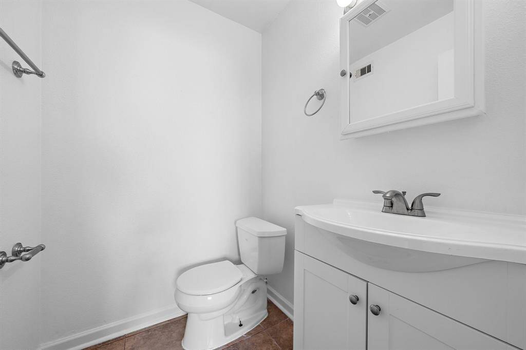 The half bath has Fresh Paint, neutral Ceramic Tile Flooring, a mirror that doubles as a medicine cabinet, "Hollywood" lighting over a white Wooden Sink Vanity Cabinet, and modern fixtures and finishes!!