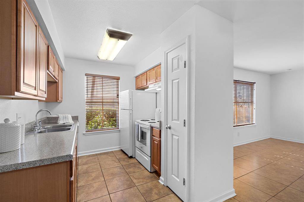 The kitchen has Fresh Paint, neutral Ceramic Tile flooring, Faux Granite Countertops, nice Wooden Cabinets, a Pantry, a Large Window with nice Wooden Blinds that let in lots of natural light when open, and modern fixtures and finishes!!