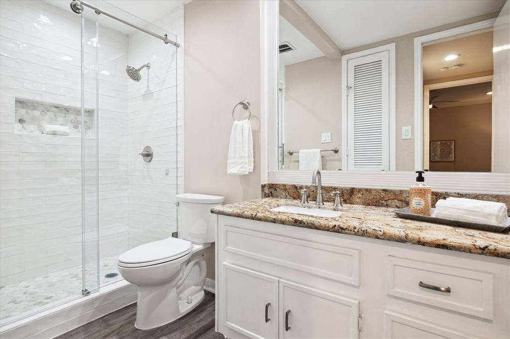 The secondary bathroom is located near the secondary bedroom and front entry way.  The shower has been rennovated and updated with a large glass sliding door.  Granite counterop on the vanity, framed mirror and a seperate linen closet.