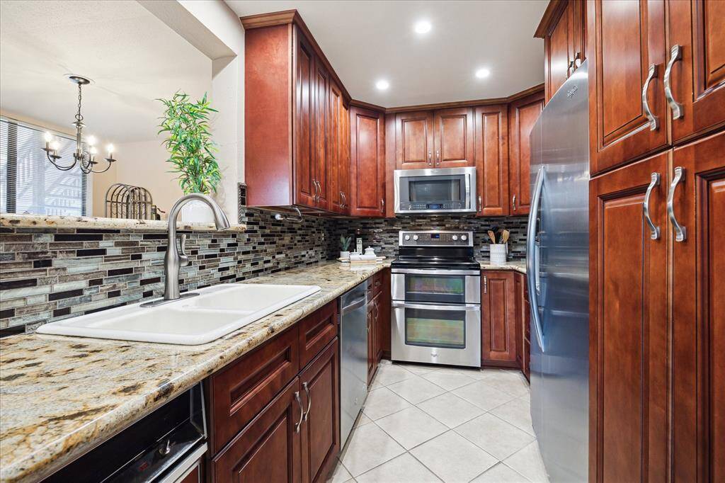 This handsome galley kitchen, open to the living room, offers granite countertops, stainless steel appliances, plenty of cabinet space for storage with soft closing doors and drawers, a stack washer/dryer and a pantry hidden behind mirrored doors.