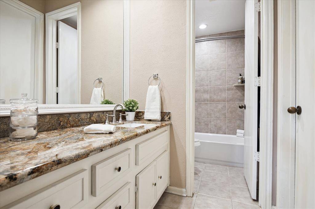 The primary bathroom is located in the primary bedroom and offers granite countertop, large framed mirror, seperate linen closet, large walk-in closet with built-in shelving and storage, and bath tub / shower combo.