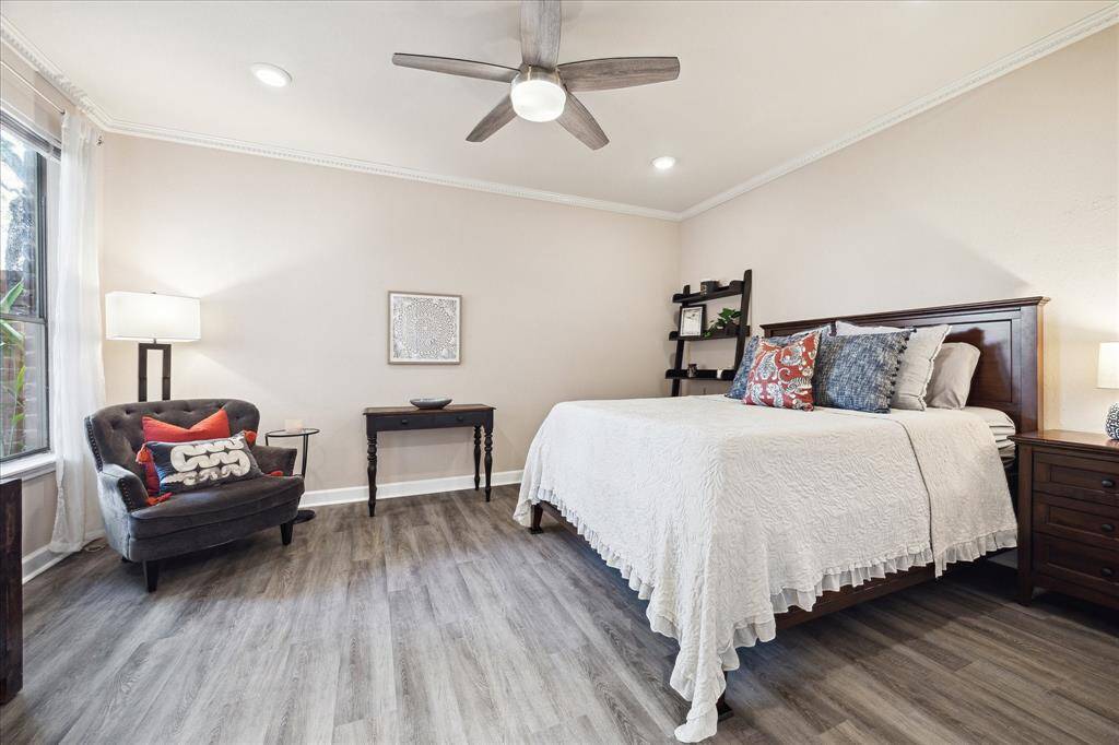 Large secondary bedroom with crown molding, ceiling fan, bright window overlooking the private patio and a large walk-in closet with building in storage.