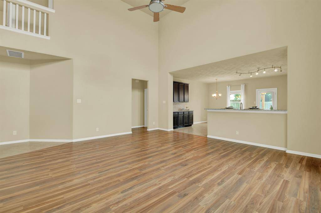 This spacious living space is designed for comfort and connection. The deep-toned flooring contrasts beautifully with the light-filled room, highlighting the home’s clean, modern aesthetic.