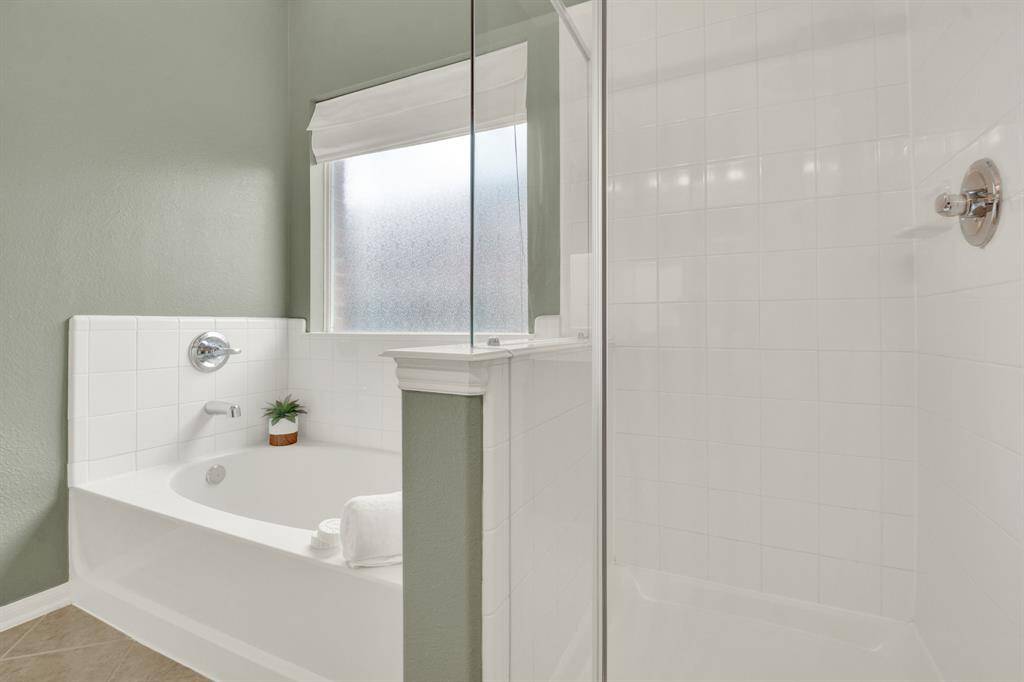 The ensuite bathroom features a generously sized soaking tub, offering a serene escape for unwinding after a long day. Adjacent to the tub, a spacious, walk-in shower provides a refreshing retreat, with thoughtfully chosen materials and a sleek design that emphasizes both style and comfort. The separation of the two elements allows for a spa-like experience, where you can enjoy both leisurely baths and invigorating showers with equal ease.