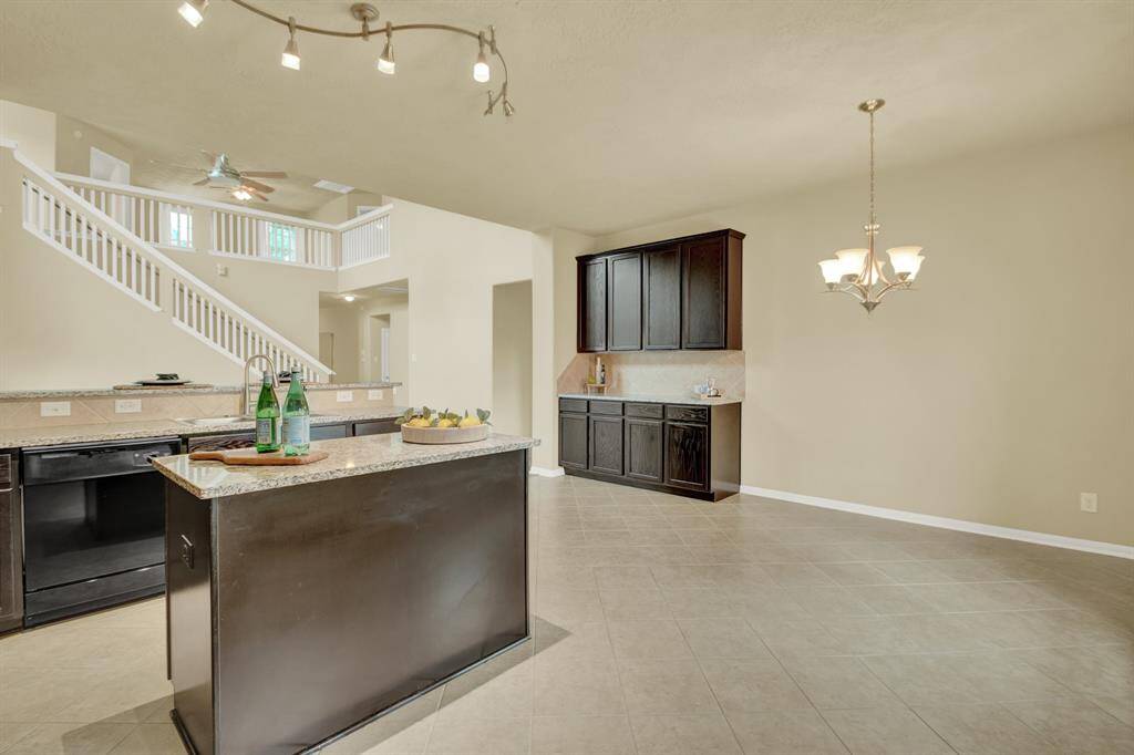 Clean, modern lighting casts a soft glow over the expansive central island, topped with sleek granite that invites everything from casual breakfasts to evening charcuterie.