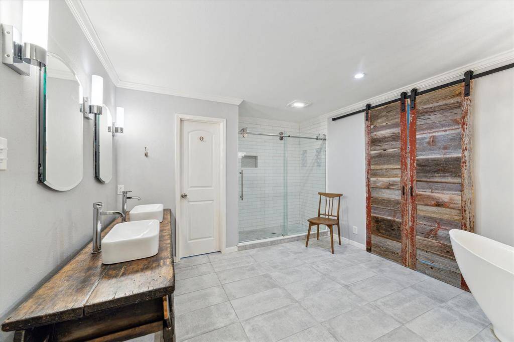 Primary bathroom - large shower.  Barn doors with rustic wood lead to a room for a closet
