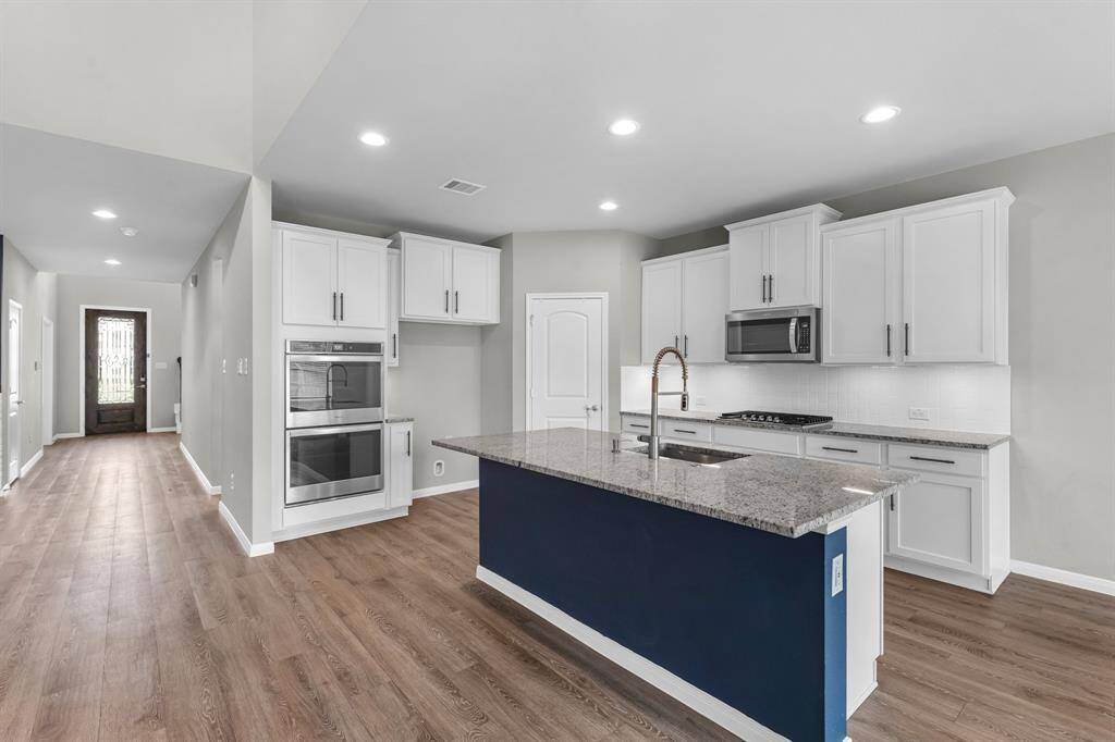 Another view of this fantastic kitchen showcases the 5-burner gas cooktop and double ovens, along with ample counter space and abundant storage—perfect for both everyday cooking and entertaining.