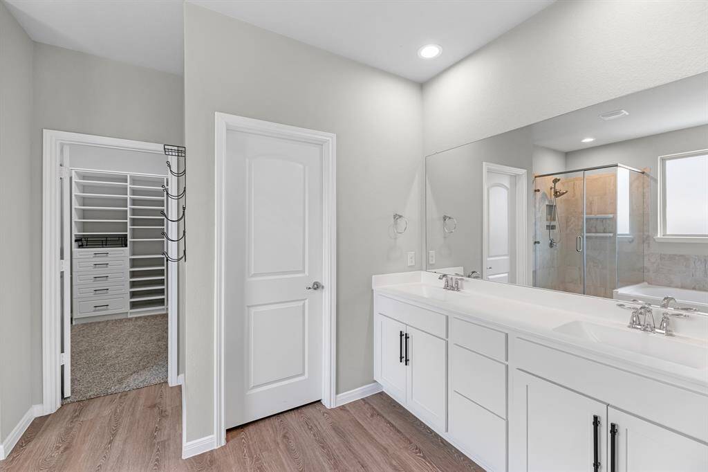 The primary bathroom offers the convenience of double sinks along with a separate tub and shower combo, providing both functionality and comfort in a stylish, spacious setting.
