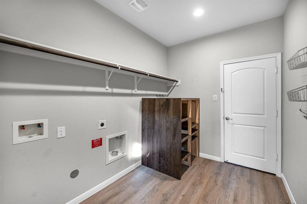 The large laundry room, conveniently located off the garage, features custom shelving for optimal organization and storage