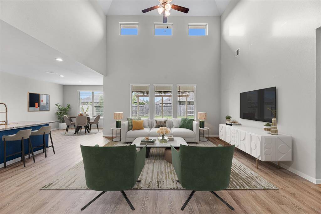 The large family room has been virtually staged to showcase its full potential. Featuring tall ceilings and upper windows that bring in an abundance of soft, indirect sunlight, this spacious area is part of an open floor plan and is perfectly positioned just off the kitchen—ideal for both everyday living and entertaining.