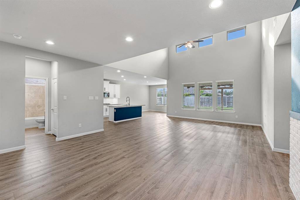 The family room and kitchen seamlessly flow into the dining room in this open-concept layout, creating a spacious and connected living area. Just off the kitchen, family, and dining spaces is a conveniently located full bathroom, perfect for guests and serving the secondary downstairs bedroom.