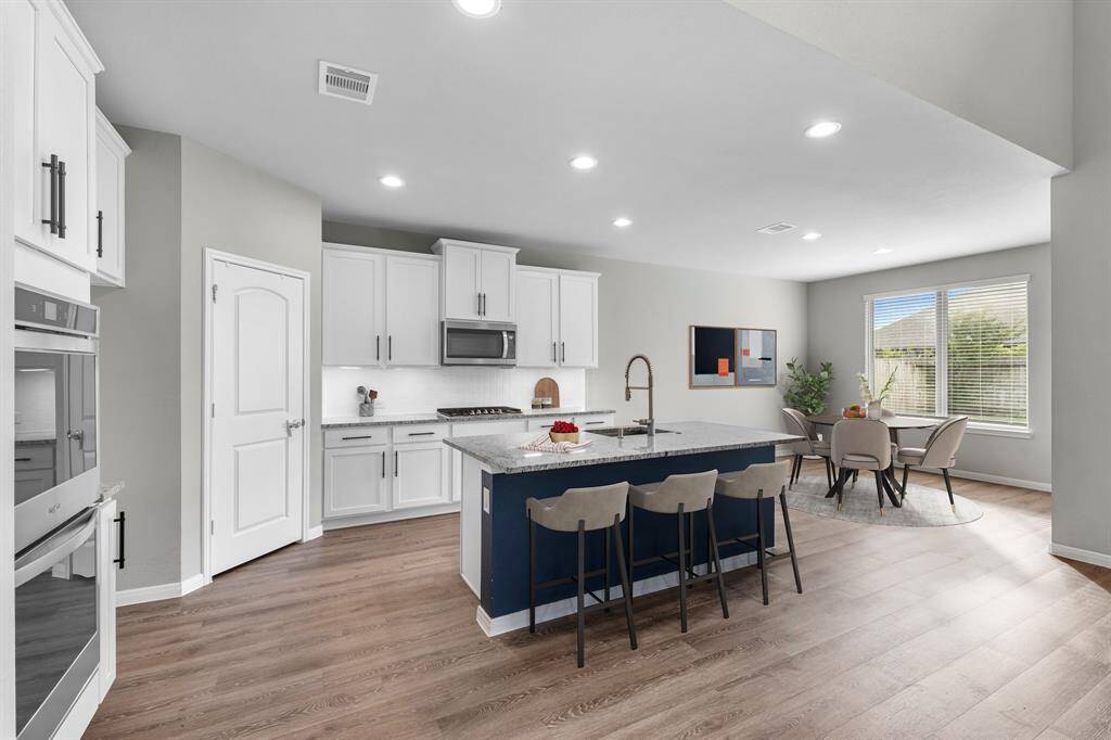 Open-concept kitchen featuring a spacious breakfast bar and a separate breakfast area overlooking the backyard.  This well-appointed kitchen also boasts a 5 burner gas cooktop and double ovens, making it ideal for cooking enthusiasts and entertaining alike.