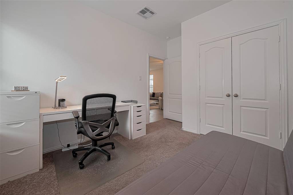 This secondary bedroom features soft natural light, a ceiling fan, and neutral tones—perfect for a guest room!