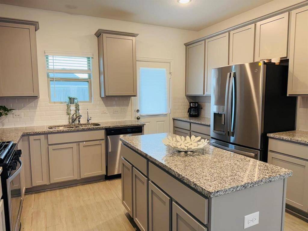 The kitchen features a stylish white subway tile backsplash, complementing the stainless steel gas range and microwave for a sleek, modern look. It's a functional and chic space that's perfect for both everyday meals and entertaining.