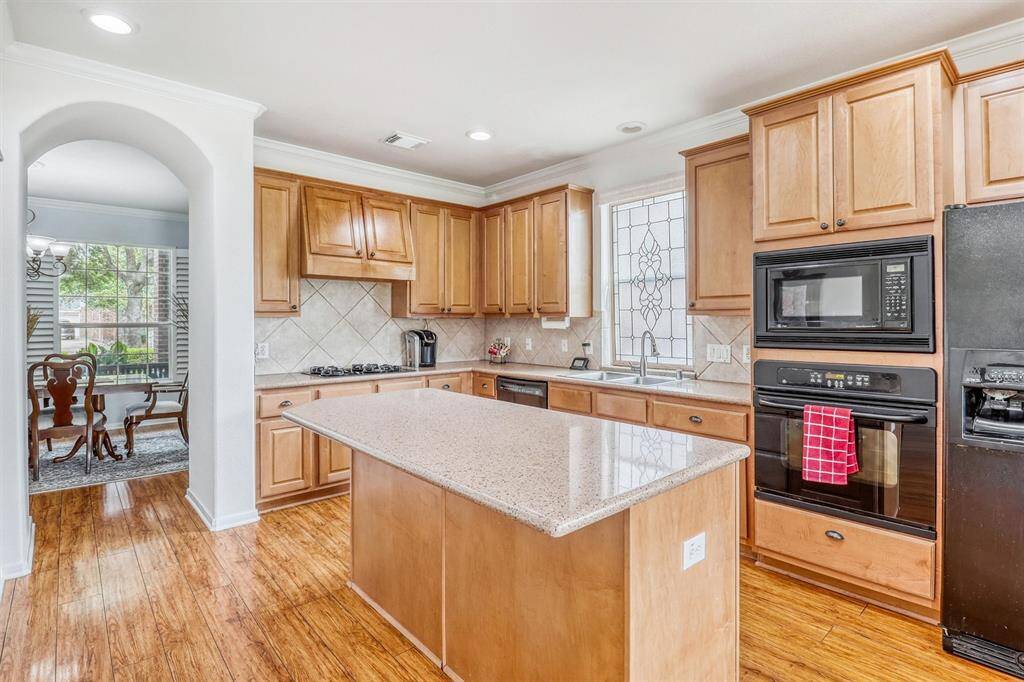 A beautiful tile backsplash brings in texture and visual interest, while a striking leaded glass window above the sink offers a charming focal point and lets in soft natural light.
