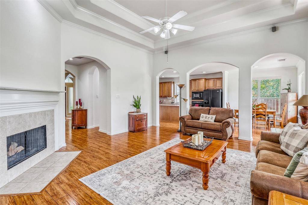 A stacked tray ceiling with intricate crown molding elevates the design of the family room, adding a refined architectural touch that draws the eye upward and enhances the sense of spaciousness.