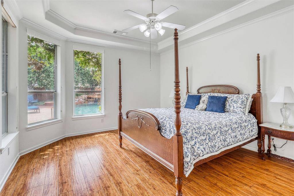 The first-floor primary retreat offers a perfect blend of luxury and tranquility, creating an ideal space to unwind. Large windows showcase stunning views of the lush backyard paradise, filling the room with natural light and a calming ambiance.