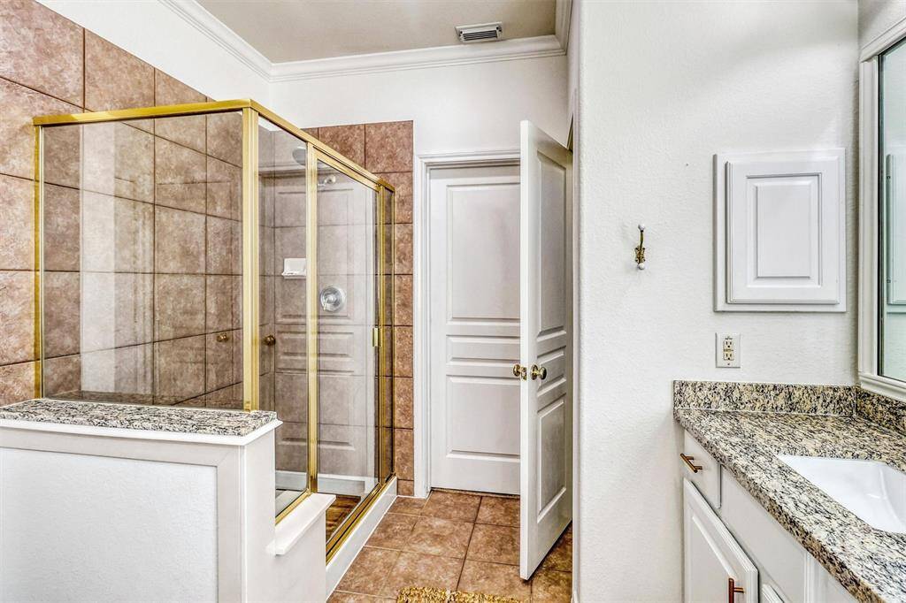 Crown molding adds a refined touch to the space, enhancing its upscale feel. For added convenience, a spacious walk-in shower features a built-in bench and sleek tile finishes—perfect for both relaxation and everyday use.
