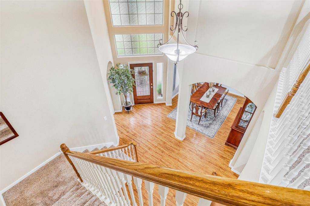 Ascend the plush carpeted staircase, accented by a rich wooden handrail, to reach the second level of the home. As you make your way up, take a moment to admire the soaring foyer below—this striking entryway offers a glimpse of the elegance and thoughtful design found throughout the home.