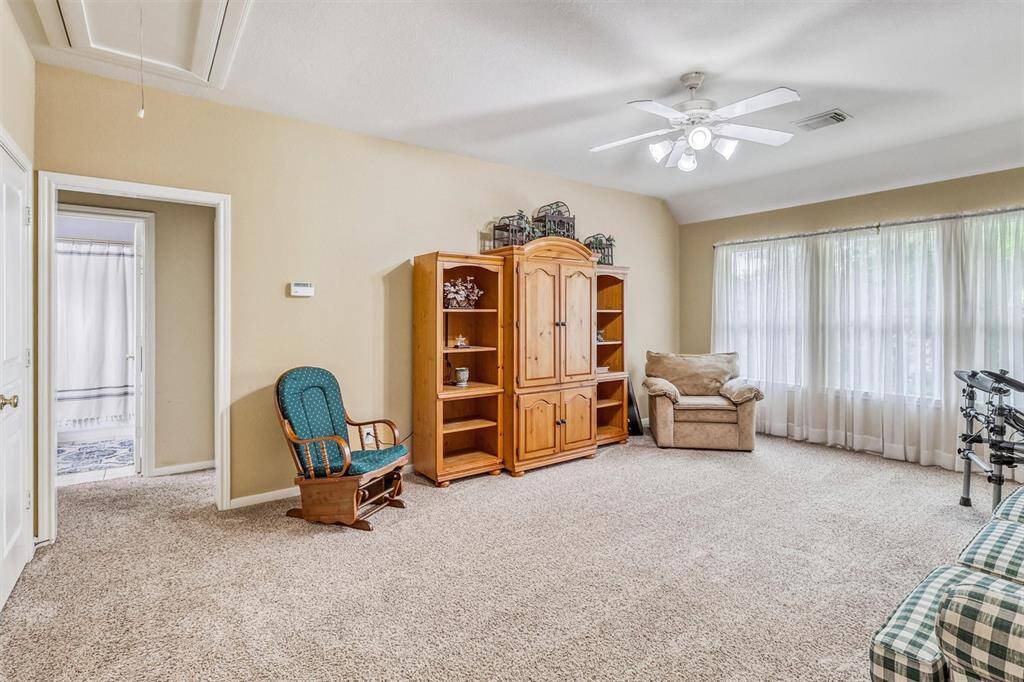 The oversized game room on the second floor offers the perfect space for fun and relaxation. It features a high ceiling with a ceiling fan for added comfort, plush carpeting underfoot, and large windows that flood the room with natural light.