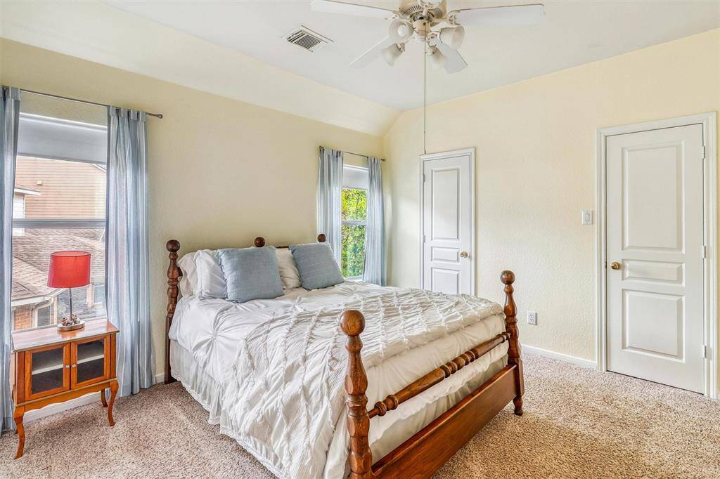The third and final secondary bedroom offers a bright and inviting atmosphere, featuring a high ceiling with a ceiling fan, soft plush carpeting, and large windows that flood the room with natural light. Spacious and comfortable, it’s an ideal space for guests, family members, or a personalized retreat.