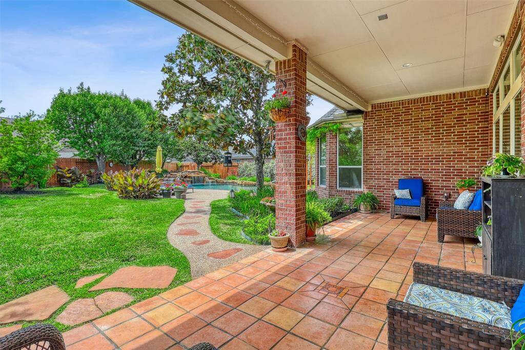 The covered patio overlooks a sprawling backyard, where an abundance of lush green space stretches out before you, providing ample room for children to play, pets to roam, or for moments of peaceful solitude.