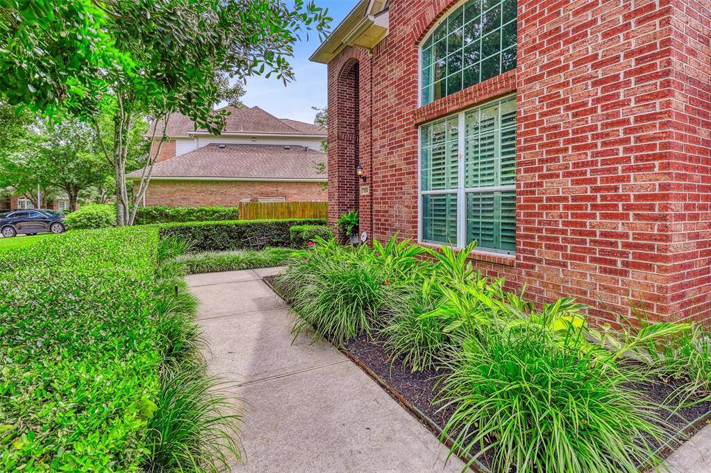 From the driveway, a paved walkway bordered by meticulously landscaped flower beds guides you to the inviting entrance of this beautiful home.