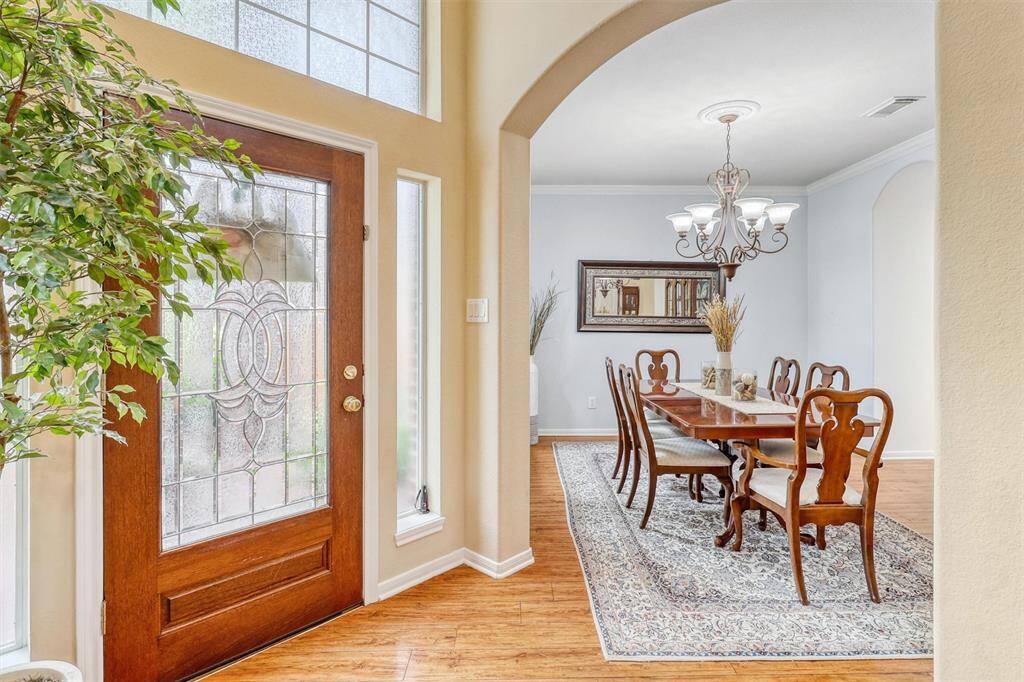 Step through the elegant leaded glass front door and into a sunlit foyer, where natural light pours in through the sidelight windows, a large transom window, and a striking arched window.