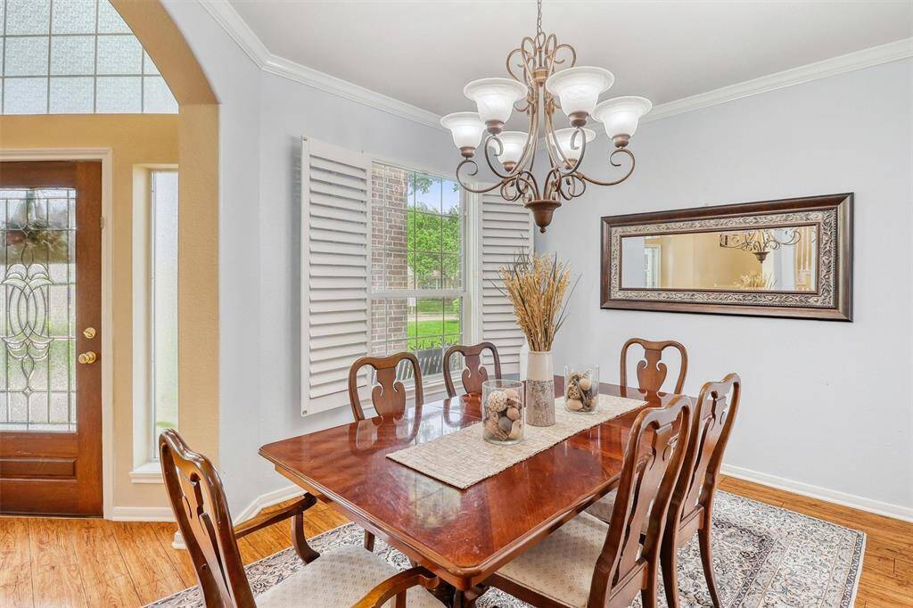 The formal dining room exudes elegance and warmth, providing an expansive setting ideal for lively family gatherings. Rich hardwood floors gleam underfoot, while a lofty ceiling is beautifully accented by an elegant chandelier and refined crown molding.