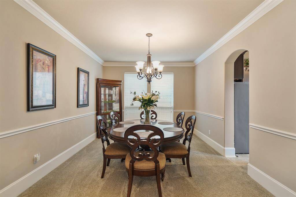 This photo showcases a cozy dining room with elegant crown molding and neutral walls. A large window provides natural light, complementing the warm ambiance.