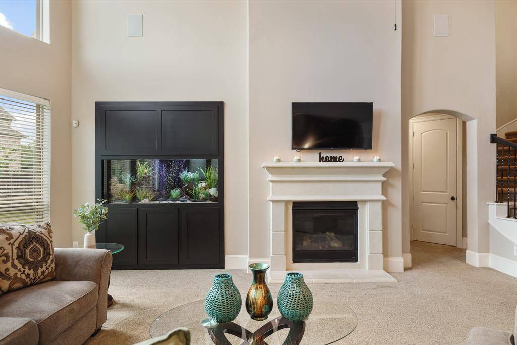This cozy living room features a modern fireplace with an elegant built-in aquarium, and a comfortable seating area. The neutral tones and decorative accents create a warm, inviting atmosphere.