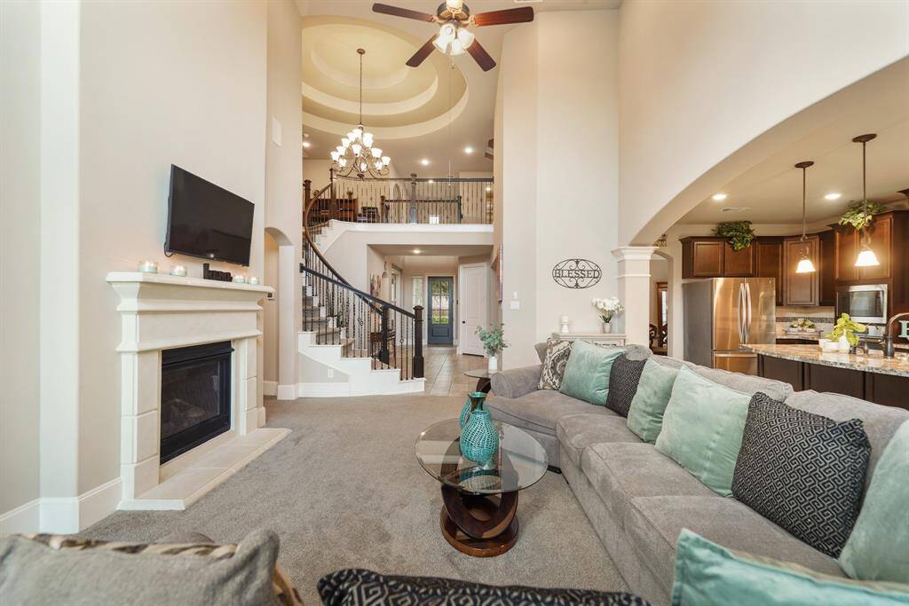 The open floor plan flows into a modern kitchen with stainless steel appliances and elegant dark wood cabinetry. The room is accentuated by soft, neutral tones and ample natural light.