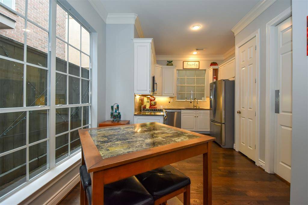 Kitchen featuring white cabinetry, stainless steel appliances, ample natural light from large windows, and a dine-in area
