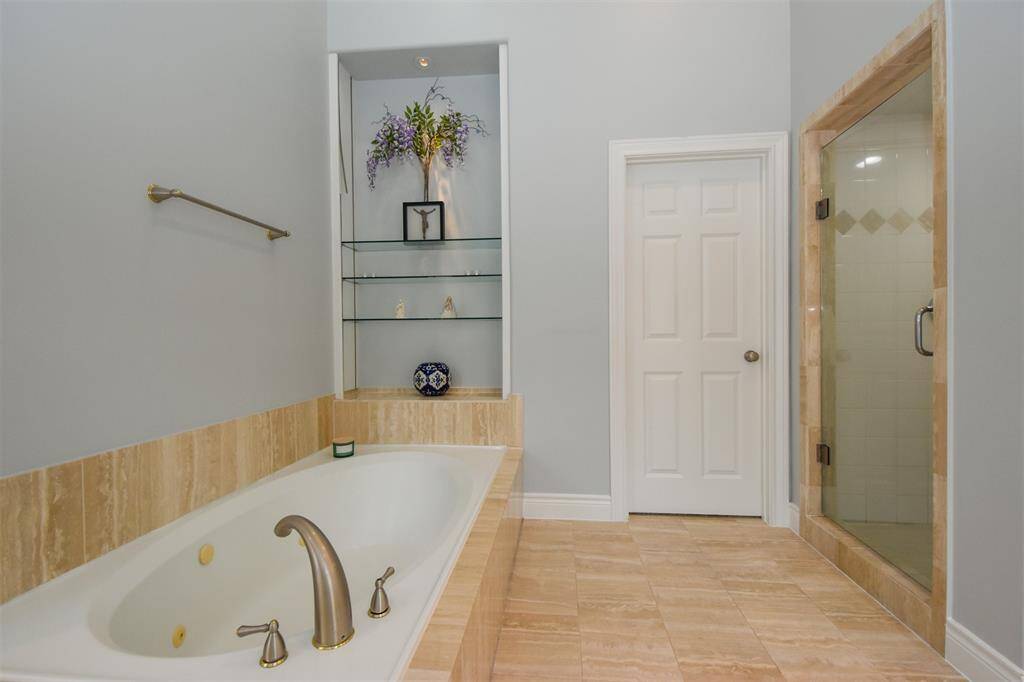 Large bathroom featuring a built-in bathtub, new fixtures, a separate glass-enclosed shower, tiled flooring, and a built-in shelving niche