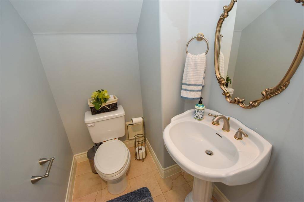 Formal powder room on the first floor featuring a pedestal sink, toilet, and an ornate mirror