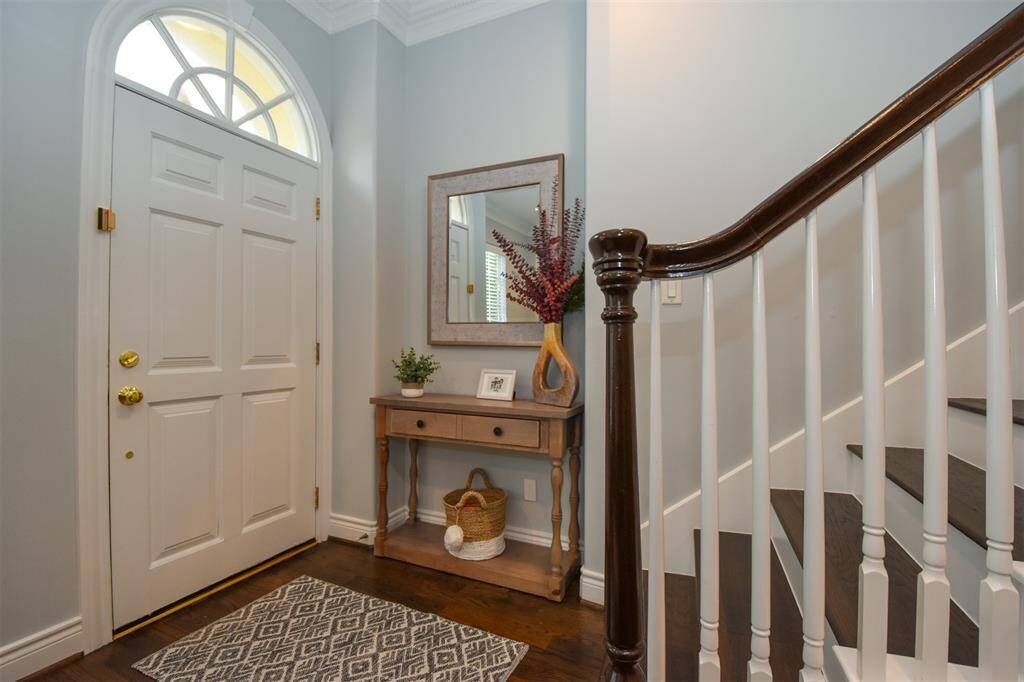 Elegant entryway featuring a hardwood staircase wleading to the primary + secondary bedrooms