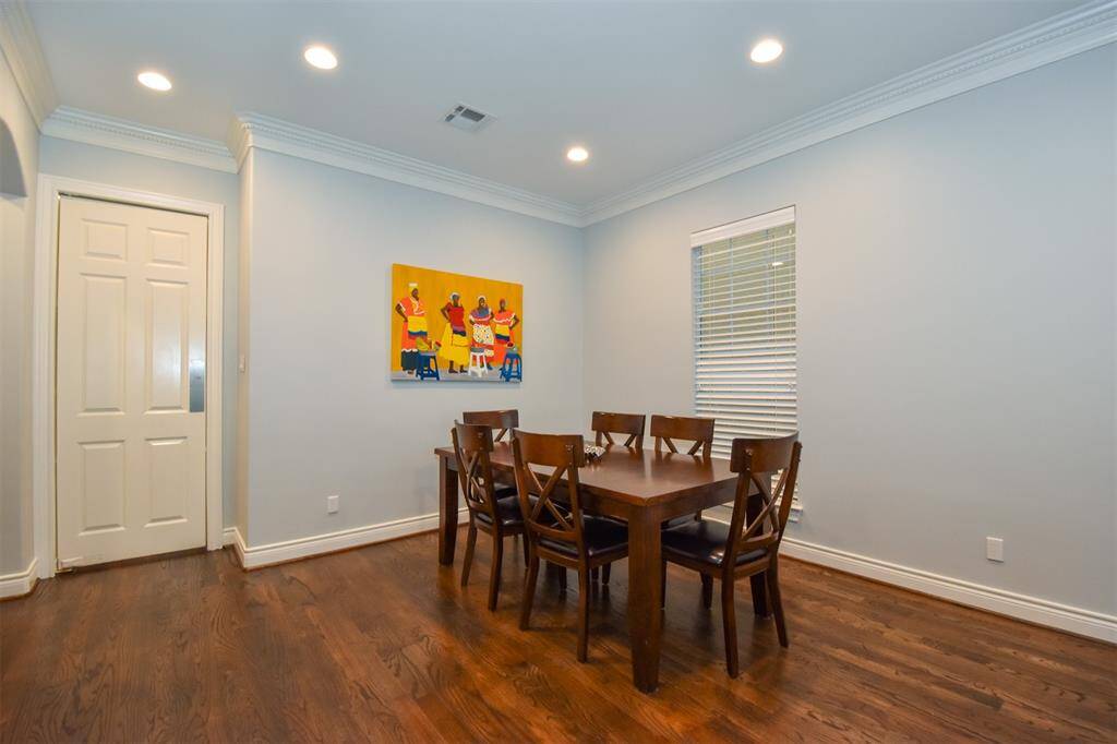 Spacious dining room with hardwood floors, crown molding, recessed lighting, a large window for natural light - door leads to the kitchen