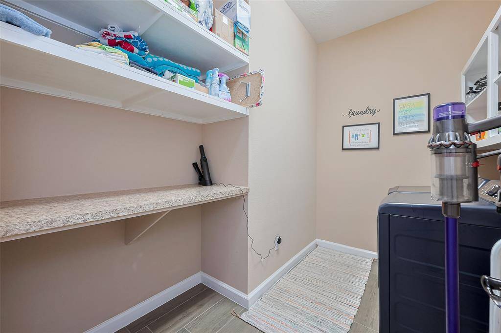 This laundry room features open shelving for storage, and a convenient countertop for folding. The space is well-organized.