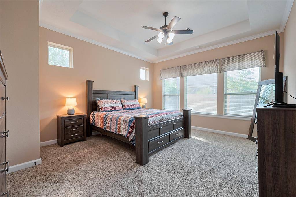 Primary Bedroom. This bedroom features a spacious and bright setting with large windows, neutral walls, and carpeted flooring.