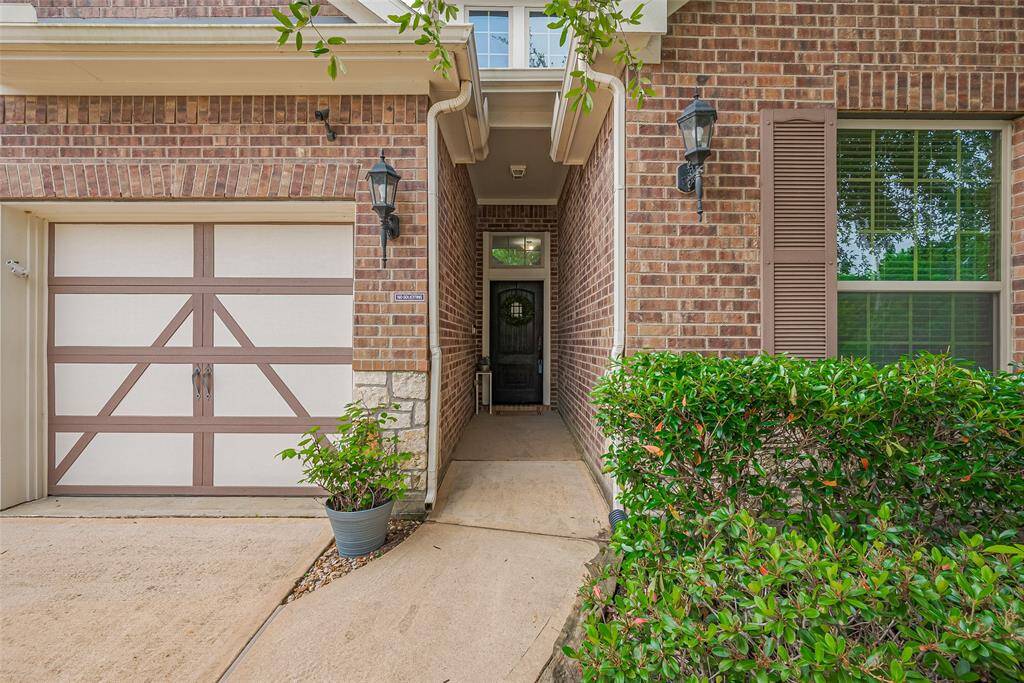 A covered entrance, complemented by well-maintained shrubbery with decorative accents and stylish outdoor lanterns, adding to its curb appeal.