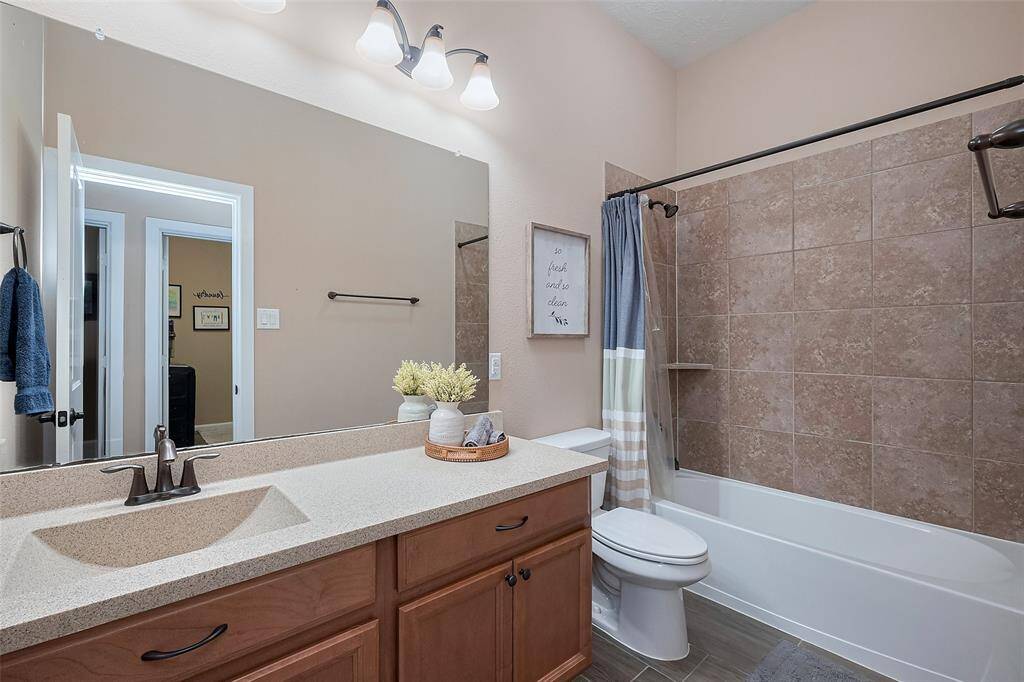 Full Bath 2: This bathroom features a modern design with a large mirror, a granite countertop, and a dark wood vanity. It includes a bathtub with a tiled shower area and a combination of neutral tones for a clean and inviting look.